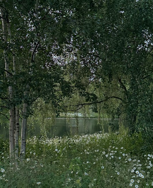 A peaceful garden scene featuring a small pond surrounded by lush greenery and wildflowers. In the foreground, a patch of white daisies and other small flowering plants grow densely along the edge of 